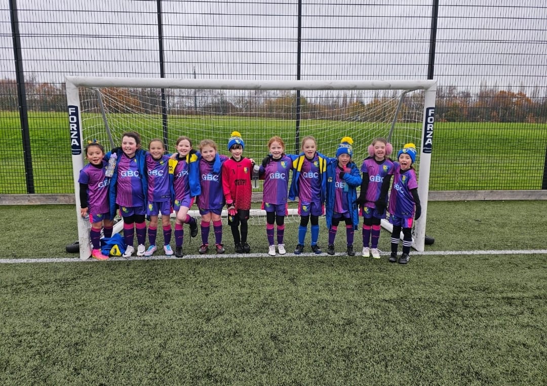 Girls football team standing in front of a goal